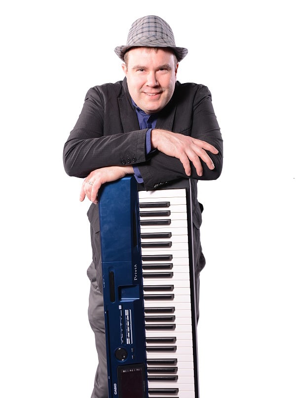 A person in a suit and hat leaning on a keyboard against a white background.
